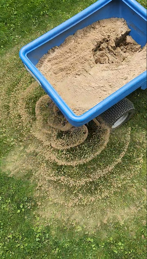 Toppdressare som sprider sand över en gräsmatta